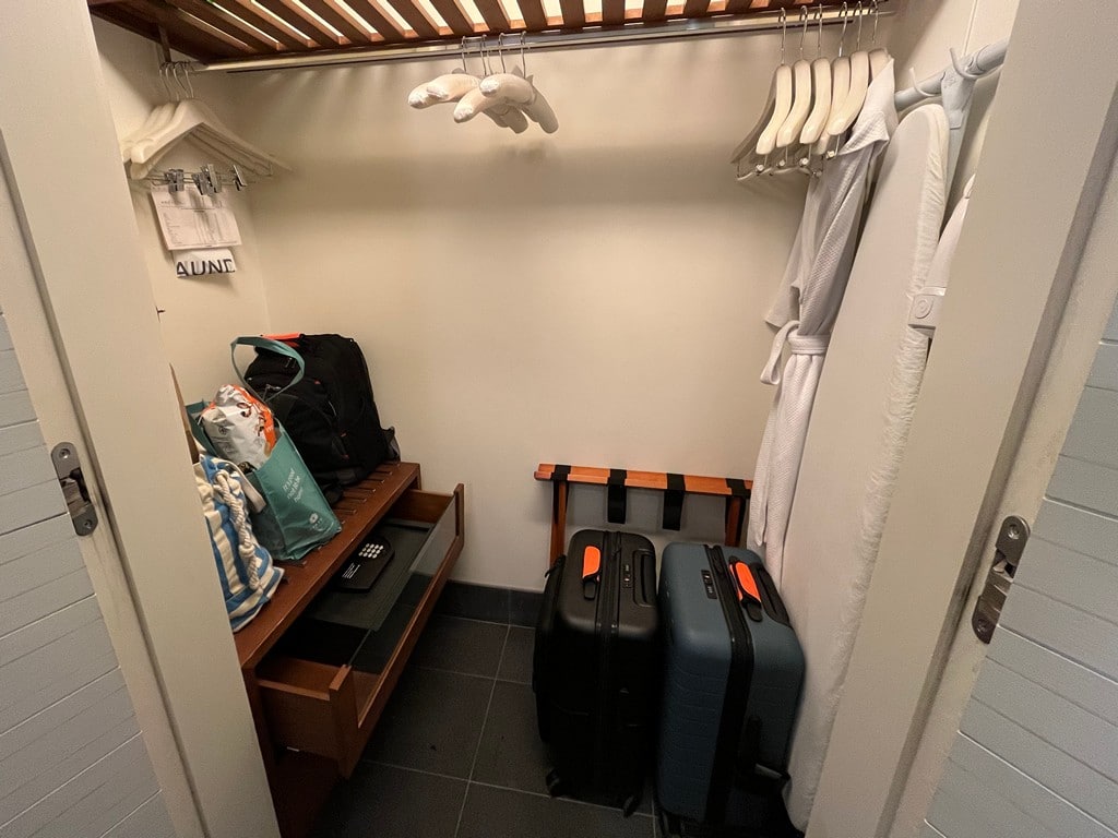 big white closet with hangers and luggage