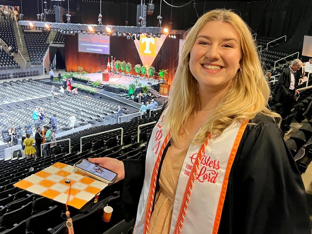 Kendall in graduation gown with Orange and White Checkerboard mortar board