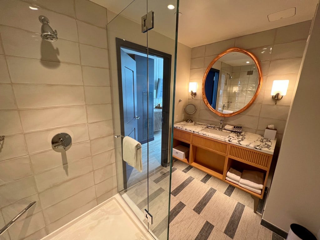 Bathroom with walk in shower and round mirror over sink at Hyatt Centric Downtown Nashville