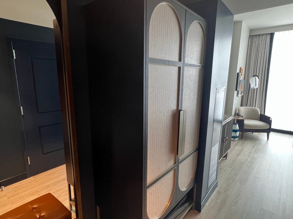 Entryway into Hyatt Centric Downtown Nashville room with mirror, armoire, chair and lamp.
