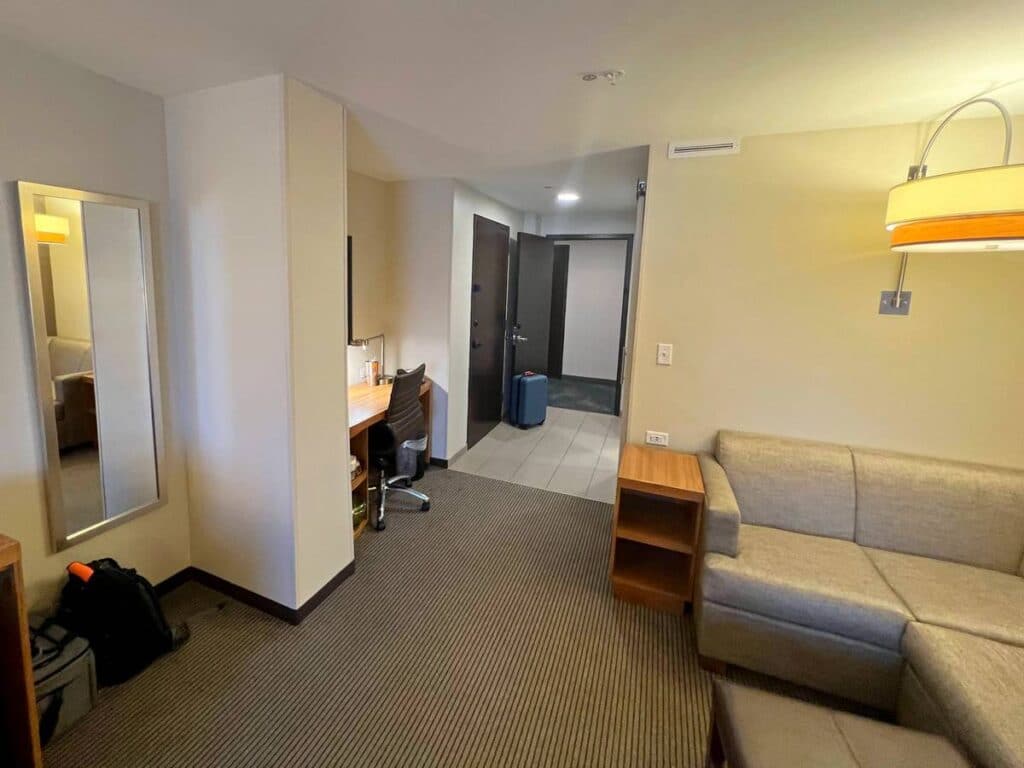 standard Hyatt Place room showing sectional couch and door to hallway and door to adjoining room
