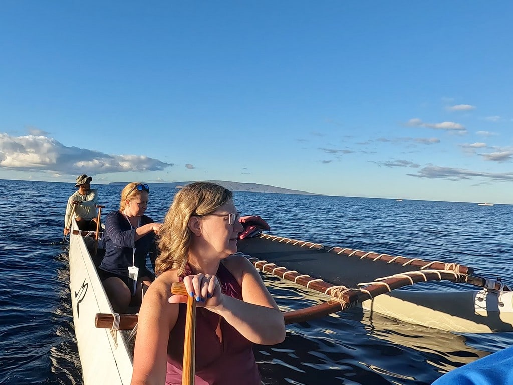 Sandra and 2 people whale watching while paddling outrigger canoe