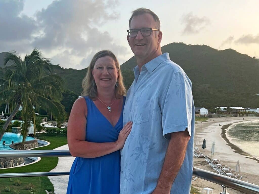 Zuzu and Ross at Secrets St Martin with palm trees, beach, pool and hills in the background.