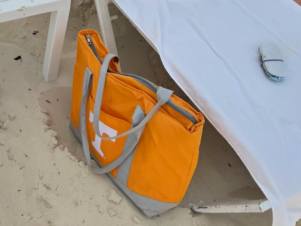 Big Orange travel cooler with Power T on the side next to a beach chair on the sand
