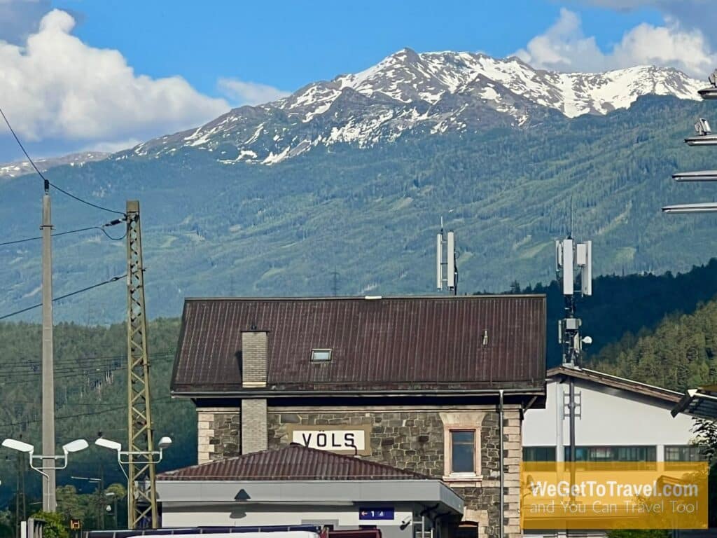 Old train station in Völs Austria with snow capped Alps in the distance.